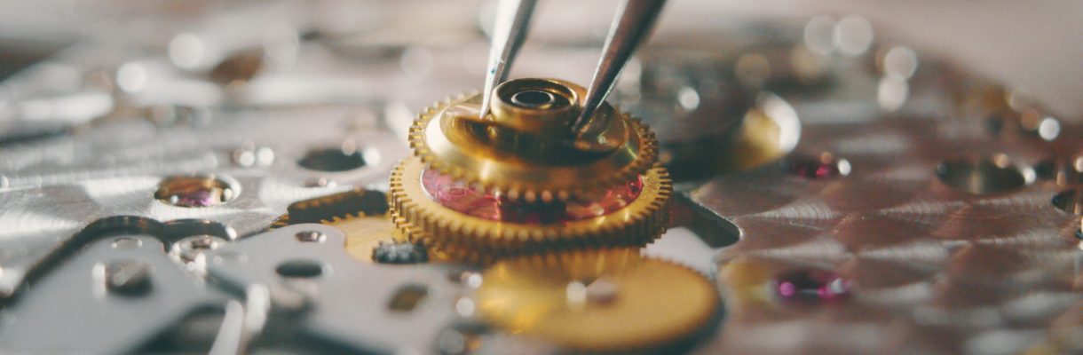 Portrait close up of a professional watchmaker repairer working on a vintage mechanism clock in a workshop.